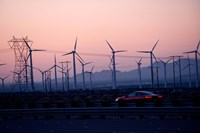 Car moving on a road with wind turbines in background at dusk, Palm Springs, Riverside County, California, USA Framed Print