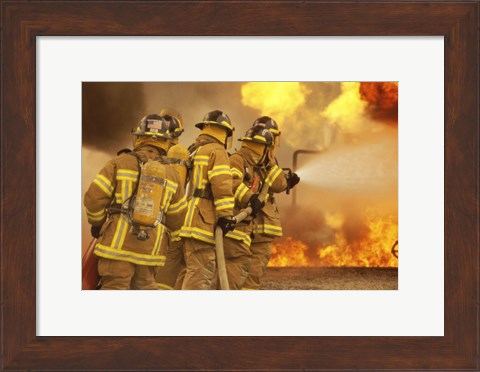 Framed Rear view of a group of firefighters extinguishing a fire and flames Print