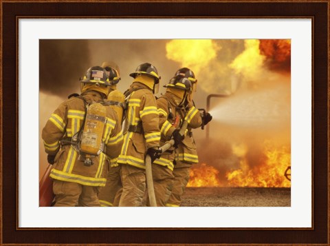 Framed Rear view of a group of firefighters extinguishing a fire and flames Print